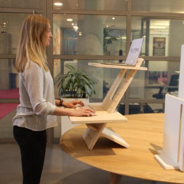 Vrouw gebruikt de You-Stand Classic zit sta bureau verhoger tijdens haar werkdag op kantoor voor een ergonomische werkplek.